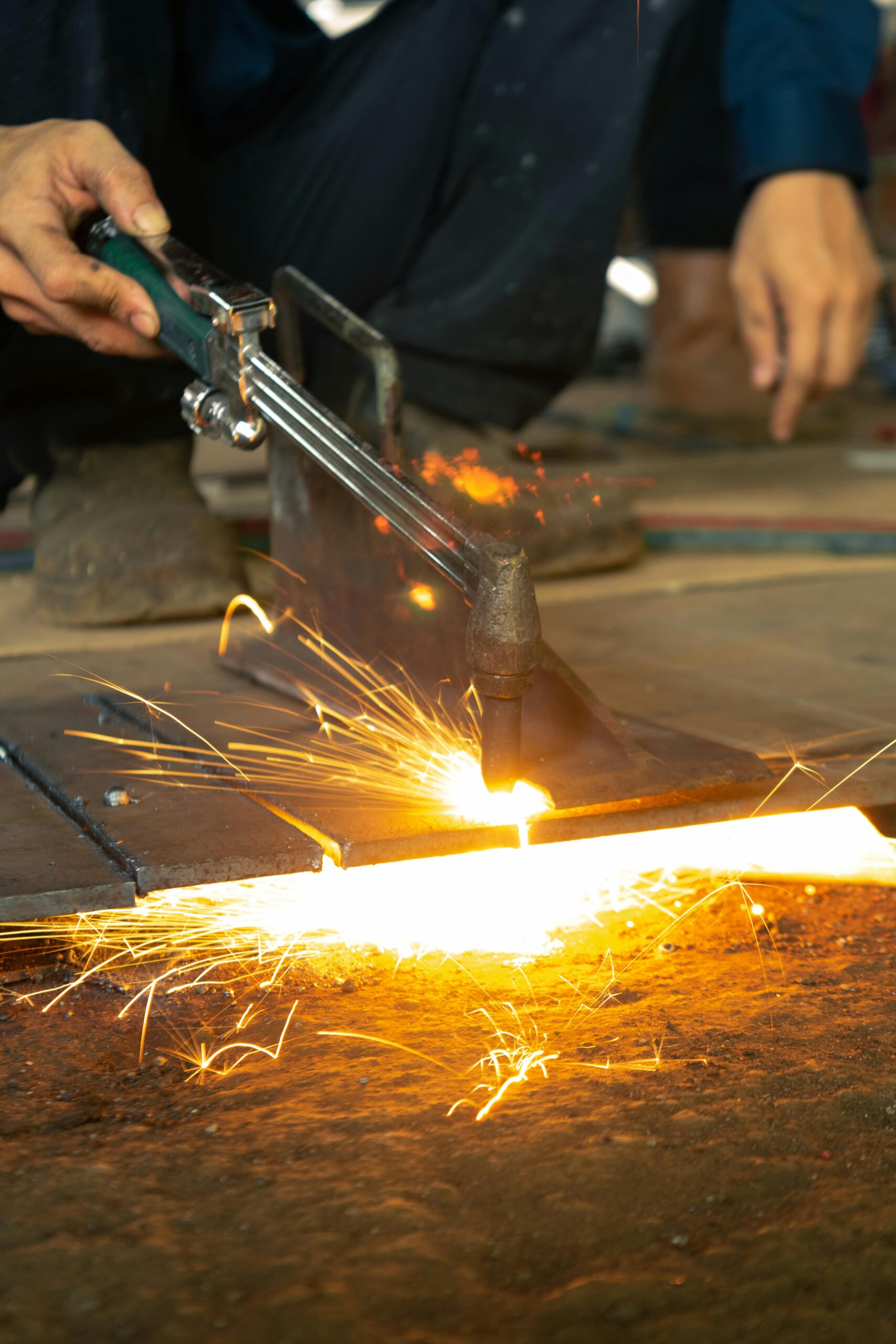 A focused industrial worker welding metal indoors, producing bright sparks.