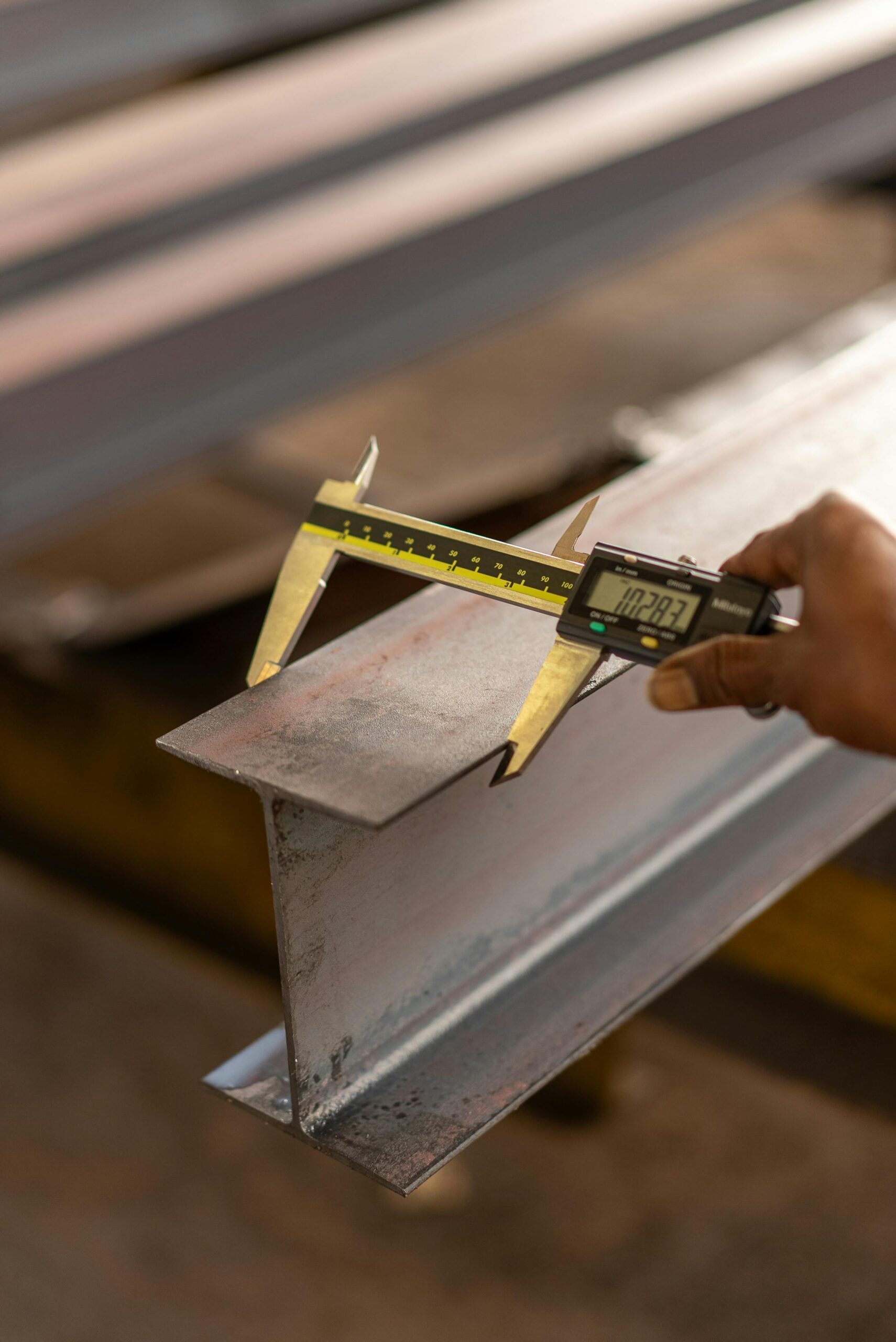 Close-up of a caliper measuring a metal beam, showcasing precision engineering and tool usage.